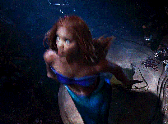 Halle Bailey's Ariel swimming quickly up to the surface