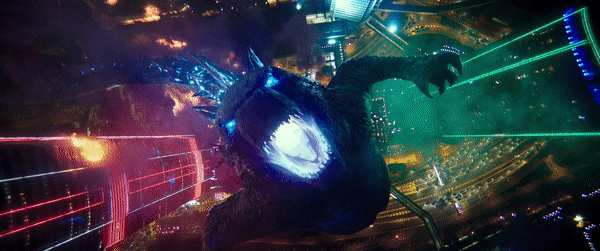 Animated GIF from a Godzilla movie showing the monster roaring triumphantly over a brightly lit cityscape at night.
